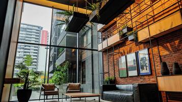 A modern interior with a glass wall, leather seating, and hanging plants.