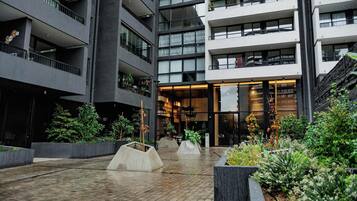 A multi-story building with balconies, a central open area with planters, and a staircase on the right.