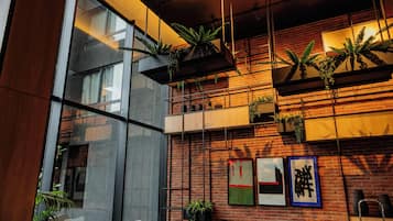 A modern interior with a brick wall, black leather sofa, and potted plants.