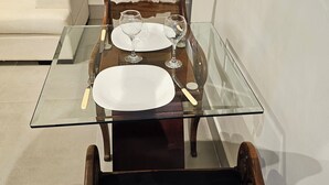 Uma mesa de jantar com cadeiras, tampo de vidro e um prato branco.