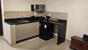 Cozinha moderna com micro-ondas, pia e bancada preta.