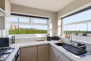 Eine moderne Küche mit einem großen Fenster, einem Herd und einem Spülbecken.