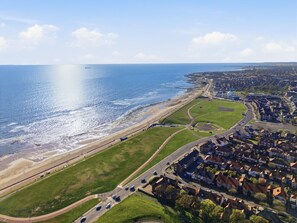 Luftaufnahme einer Küstenstadt mit Strand, Straßen und Wohnhäusern.