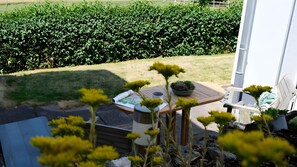 Une terrasse avec une table, une chaise et un pot de fleurs.