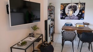 A modern living room with a flat-screen TV, a dining table with chairs, a coffee table, and a decorative wall piece. - Holiday Apartment for 2 People (40 m²) in Kerpen (Eifel) (Kerpen (Eifel))