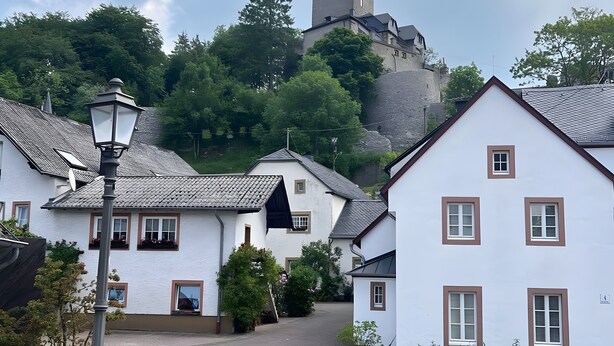 A village with traditional white houses, a street lamp, and a castle in the background. - Holiday Apartment for 2 People (40 m²) in Kerpen (Eifel) (Kerpen (Eifel))