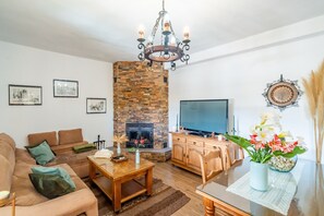 Ein Wohnzimmer mit Kamin, Sofa, Fernseher und Essbereich.