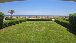 A view of a resort with a pool, palm trees, and a clear blue sky.