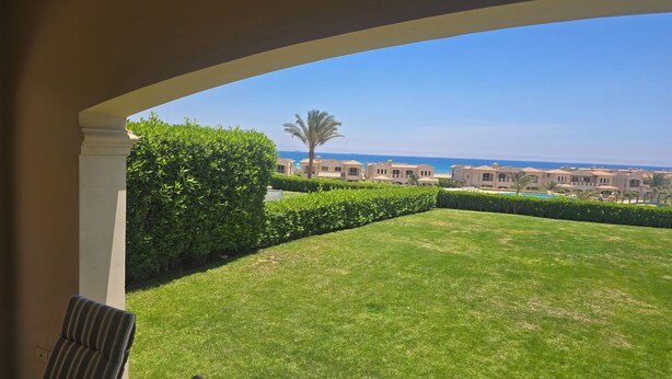 A covered outdoor area with a view of a pool and buildings in the distance.