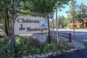 Schild für Château de Montagne mit Berg-Symbol, umgeben von Grünpflanzen und Felsen.