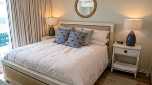 Ein Bett mit weißer Bettwäsche, ein Nachttisch mit Lampe und ein Spiegel an der Wand.