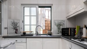 A modern kitchen with white cabinetry, a stainless steel sink, a microwave, and a gas stove. - Manuel Vaz House near Tavira (Tavira)