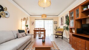 A living room with a sofa, coffee table, dining table, chairs, and a TV stand. - Manuel Vaz House near Tavira (Tavira)