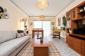 Ein Wohnzimmer mit Sofa, Couchtisch, Esstisch, Stühlen und einem Fernsehschrank.