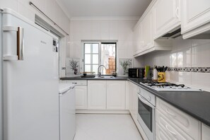 Eine moderne Küche mit weißen Schränken, einem Edelstahlkühlschrank, einem Gasherd und einem Geschirrspüler.