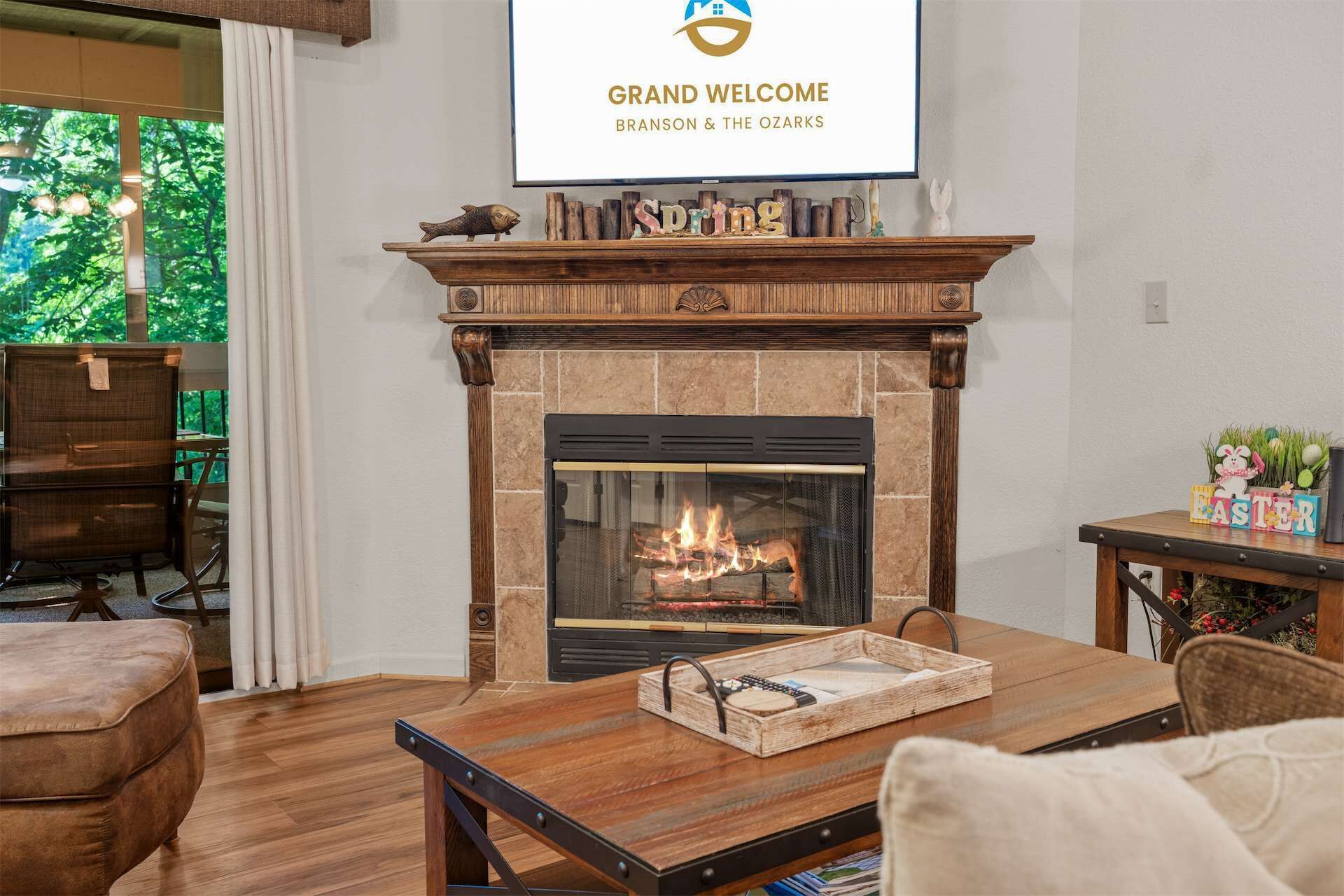 Un salon doté d’une cheminée, d’un téléviseur diffusant l’émission « Grand Welcome Branson & The Ozarks », et d’un coin repas avec une table et des chaises en bois.