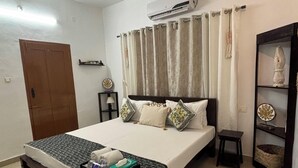 Ein Schlafzimmer mit einem Bett, einem Deckenventilator, einer Klimaanlage, einem Regal mit Dekoration und einer Tür.