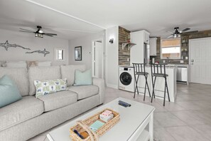 A compact living space with a sofa, a coffee table, a washing machine, and a dining area. - Spectacular Gulf Views Close To Beach Studio 4606 (Bonita Springs)