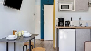 Una cocina moderna equipada con microondas, cafetera y lavavajillas. Hay una mesa de comedor con cuencos y vasos.