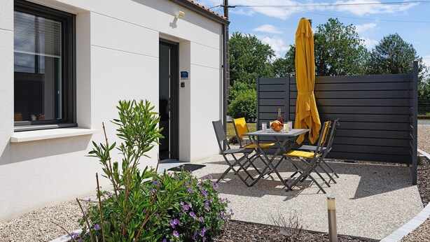 Un edificio con puerta, ventana y un patio con mesa y sillas.