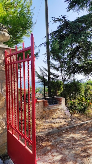 Una verja metálica roja, un muro de piedra y una chimenea de ladrillo.