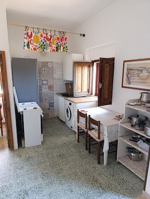 Una cocina compacta con lavadora, una mesita y zona de comedor.