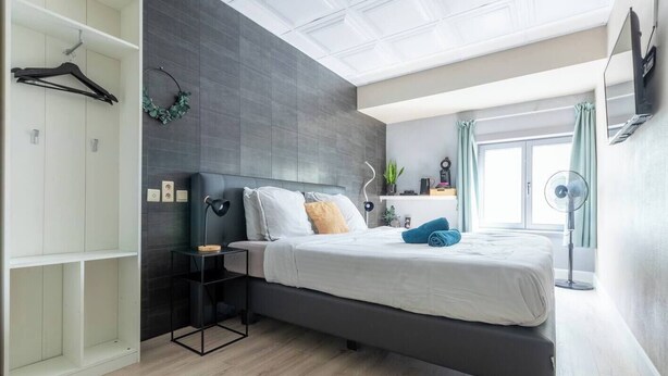 Een moderne slaapkamer met een bed, nachtkastje en een kledingkast.