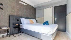 Een moderne slaapkamer met een bed, nachtkastjes, een bureau en een kledingkast.