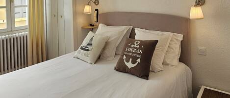 A neatly made bed with pillows, a bedside lamp, and a small table beside it.