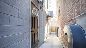 A narrow alleyway with a mailbox, a door, and a brick wall. - Casa Hotels | Stylish Suite with Private Patio (Toronto)