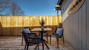 A wooden deck with a table and chairs, a 'HOME' sign, and a wooden fence. - Casa Hotels | Stylish Suite with Private Patio (Toronto)