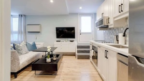 A modern apartment with a living room, kitchen, and a TV. - Casa Hotels | Stylish Suite with Private Patio (Toronto)