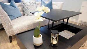 A living room with a sofa, a coffee table, a potted plant, and an hourglass. - Casa Hotels | Stylish Suite with Private Patio (Toronto)