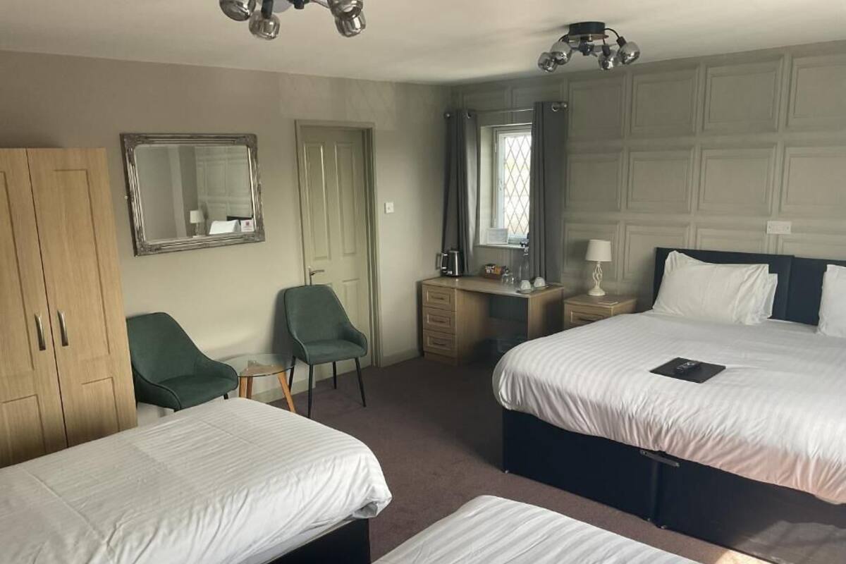 Habitación de hotel con dos camas, un escritorio, una silla, un armario y un espejo.