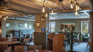 A restaurant with round tables, chairs, and hanging light fixtures. - The Throckmorton (Alcester)
