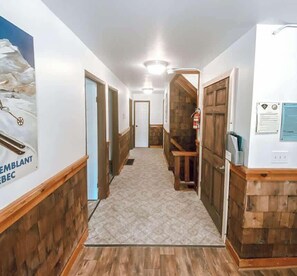 Un couloir aux murs en bois, orné d’un tapis à motifs et dont les portes donnent accès à différentes pièces.