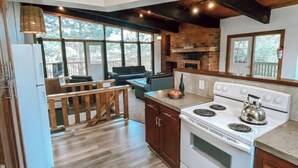 A kitchen with a stove, cabinets, and a dining area with a bench.
