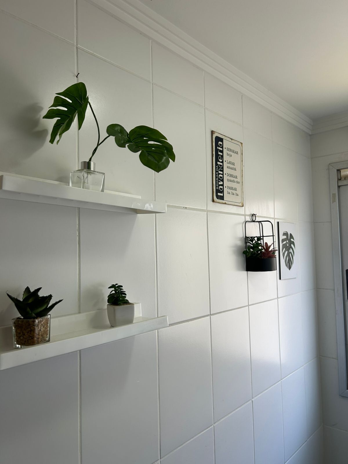 Une salle de bain avec des murs recouverts de carreaux blancs, un espace douche et un panneau avec du texte en portugais.
