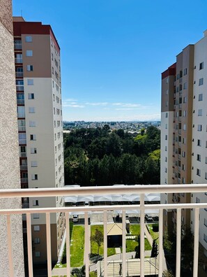 Un immeuble de grande hauteur doté de nombreux balcons, offrant une vue sur le paysage urbain et donnant sur un espace vert aménagé en parc.