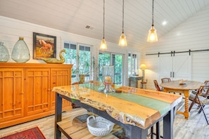 A kitchen with a wooden island, pendant lights, and a dining area with a wooden table and chairs.