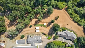 An aerial view of a residential area with multiple houses, a dirt path, and surrounding greenery.