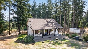Une maison de plain-pied avec un porche, entourée d’une forêt.
