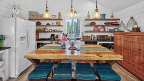 Une cuisine dotée d’un îlot central en bois, de luminaires suspendus et de divers ustensiles de cuisine rangés sur des étagères.