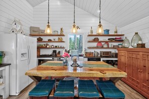 Una cocina con una isla de madera, lámparas colgantes y diverso menaje de cocina en estantes.