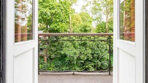 A balcony with a wrought iron railing and a view of a green park. - Hotel Entree - Private Balcony View of Canal (Brugge)
