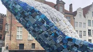 Escultura de ballena hecha con objetos apilados en un espacio público.