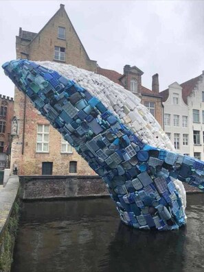 Escultura de ballena hecha con objetos apilados en un espacio público.