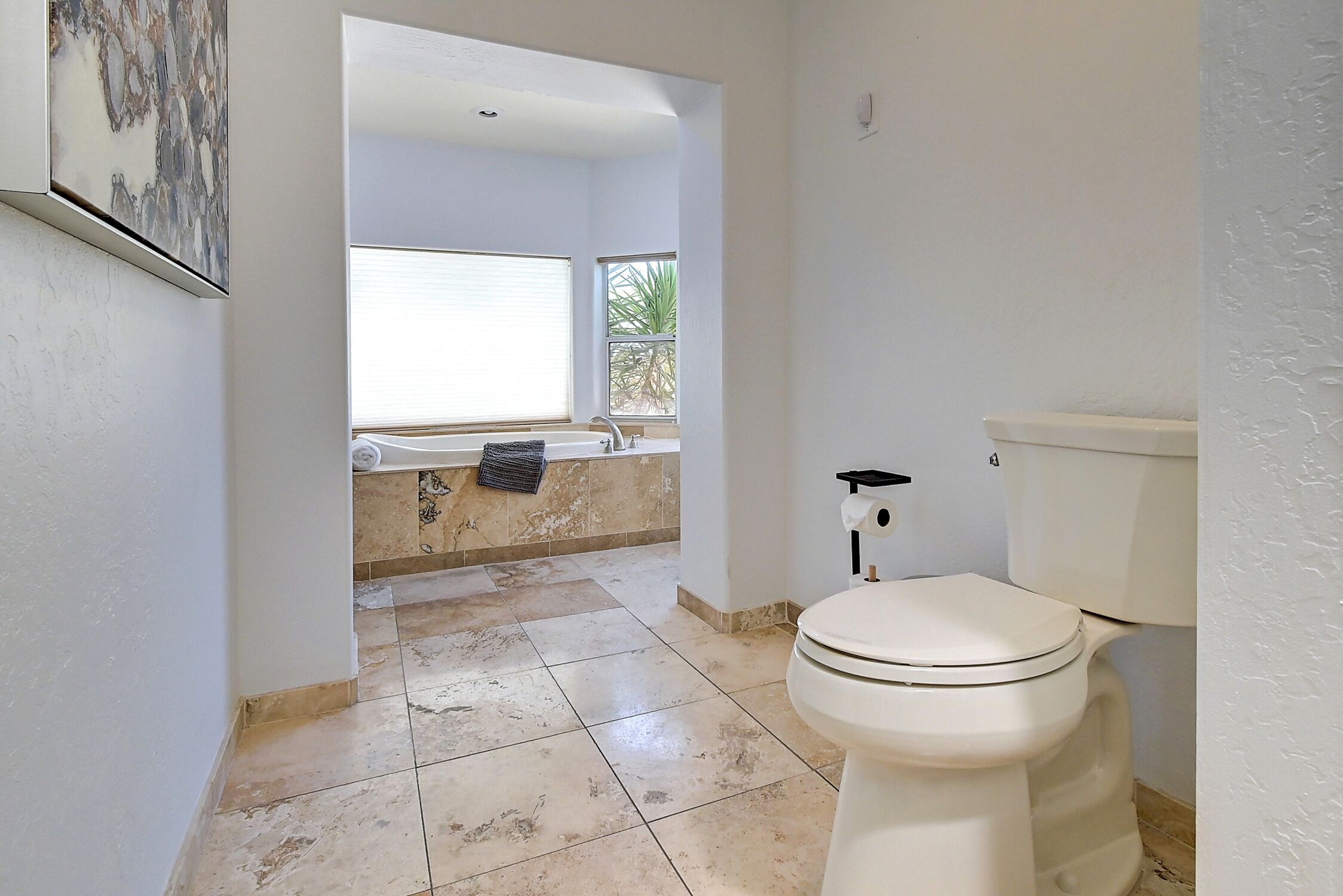 A bathroom with a toilet, a bathtub, and a window.