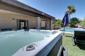 Ein Whirlpool, Sitzgelegenheiten im Freien und ein Poolbereich mit Palmen.