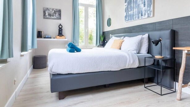 Una camera da letto moderna con un letto, comodino, lampada e un'opera d'arte.